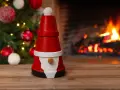 En söt tomte gjord av krukor står framför en sprakande brasa och en julgran. Perfekt för att måla tomte-pyssel.