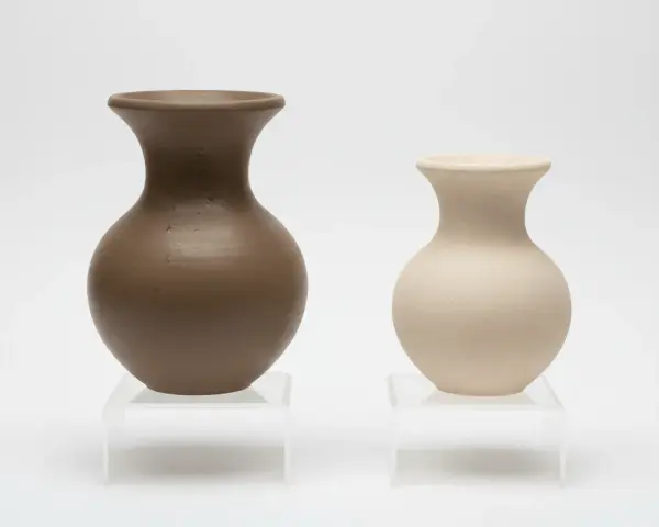 Två vaser, en i mörkbrun och en i ljusbeige, som om de vore formade av blå lera.